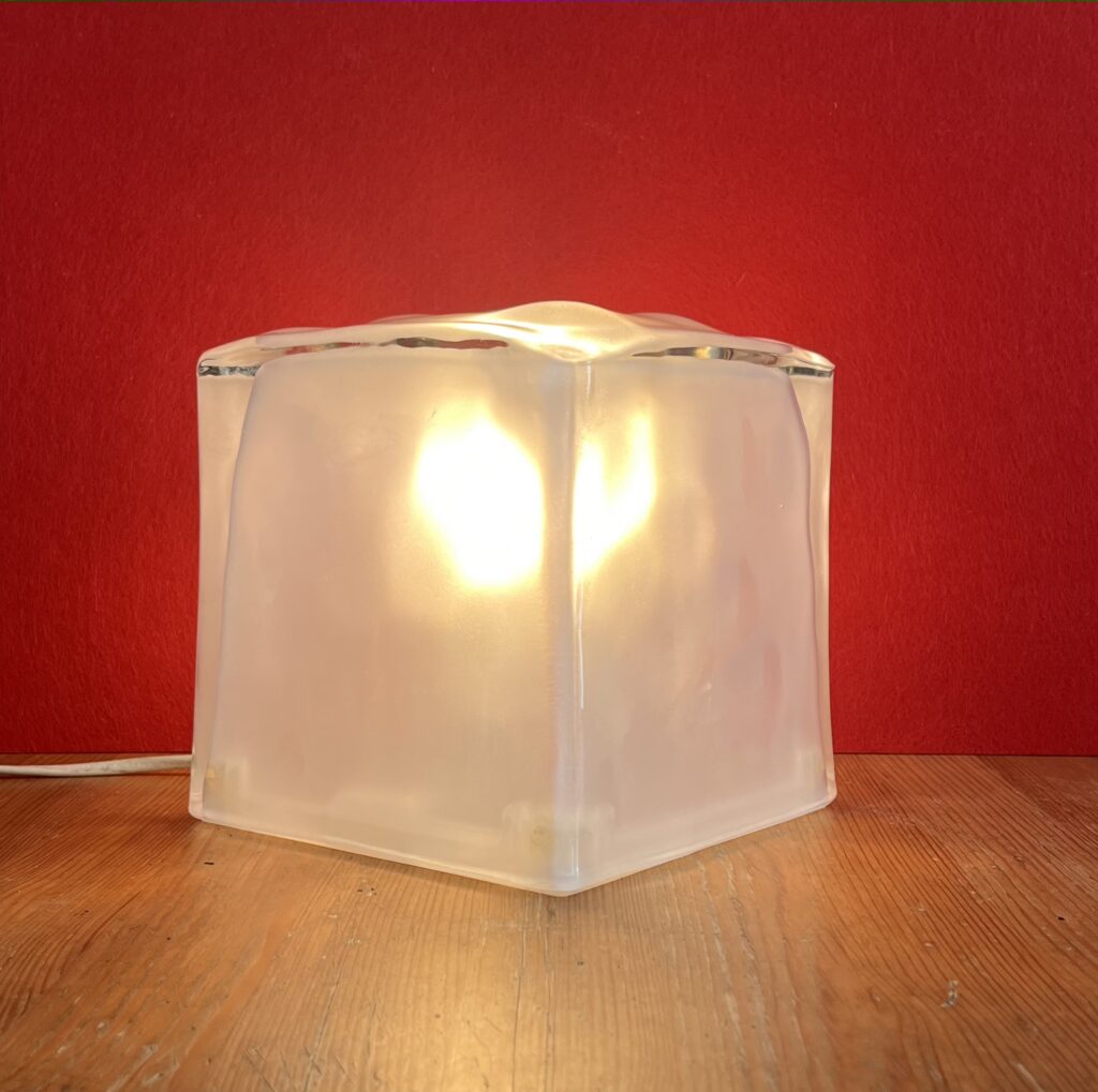 Lampada da tavolo vintage IKEA IVIKEN con diffusore cubico in vetro satinato rimosso, base bianca e lampadina accesa, fotografata su piano in legno.