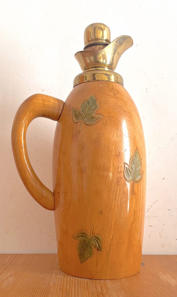 Thermos vintage Macabo in legno color miele con foglie intagliate, manico curvo e beccuccio metallico dorato, Italia anni ’50.