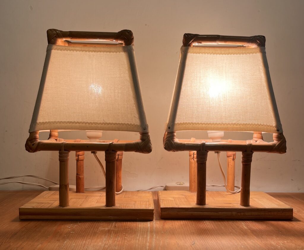 Coppia di lampade da tavolo vintage in bambù naturale con basi rettangolari, dettagli intrecciati e paralumi trapezoidali in tessuto avorio.